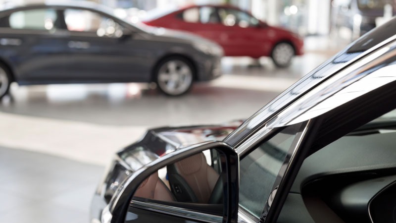 Macchina grigia, nera e rossa parcheggiate in una concessionaria 